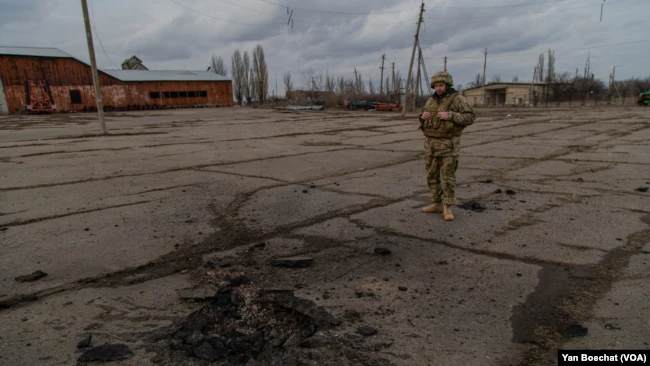 Un soldado ucraniano observa el lugar donde cayó una bomba que mató a otro soldado no lejos de la línea del frente en el este de Ucrania, el 19 de febrero de 2022, en Novoluganske, Ucrania. (Yan Boechat/VOA)