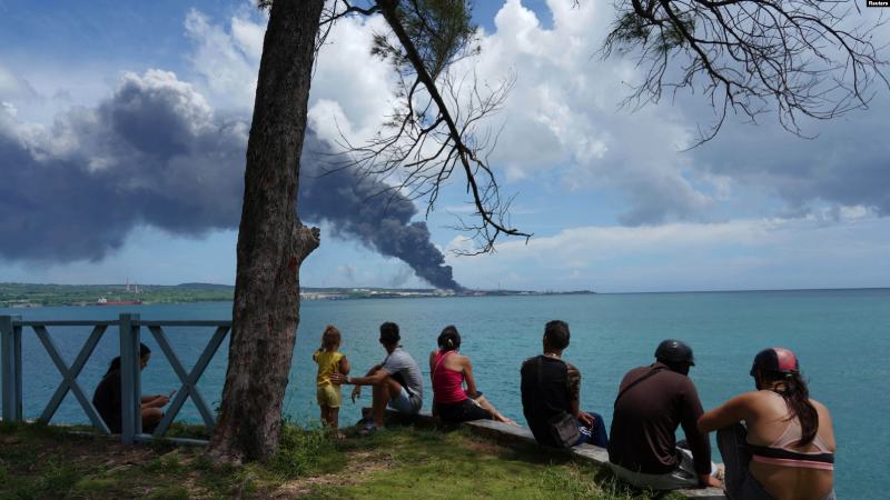 La gente observa cómo se eleva el humo sobre los tanques de almacenamiento de combustible que explotaron cerca del puerto de supertanqueros en Matanzas, Cuba, el 7 de agosto de 2022. REUTERS/Alexandre Meneghini